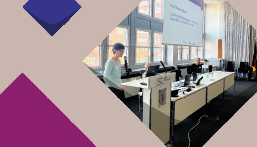 Eine lila Kacheln der KSL.NRW und ein Foto von KSL.Münster-Mitarbeiterin Martina Steinke spricht an einem Stehpult in ein Mikrofon. Dabei blickt sie auf den Laptop, der vor ihr steht. Neben dem Pult steht ein langer Tisch, an dem zwei weitere Personen sitzen. Über ihnen wird die Bildschirmpräsentation mit dem Veranstaltungsthema an eine Leinwand projiziert.