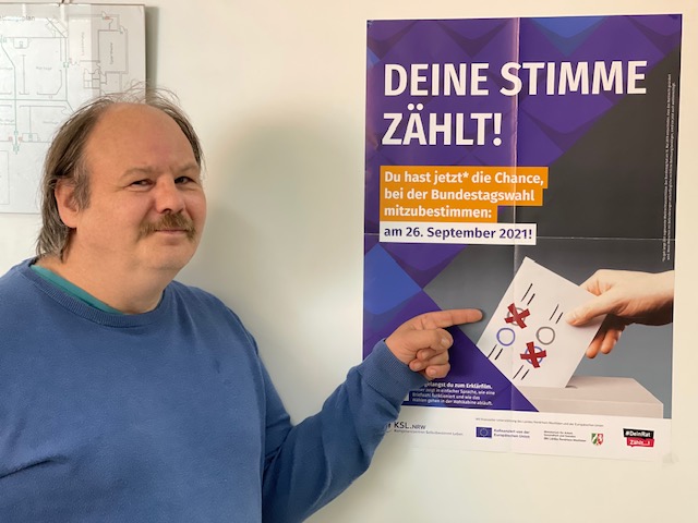 Man sieht Gerd Ziegler der auf ein Plakat der Kampagne &quot;Deine Stimme Zählt&quot; zeigt