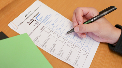 Person bearbeitet ihren Stimmzettel bei einer Wahl