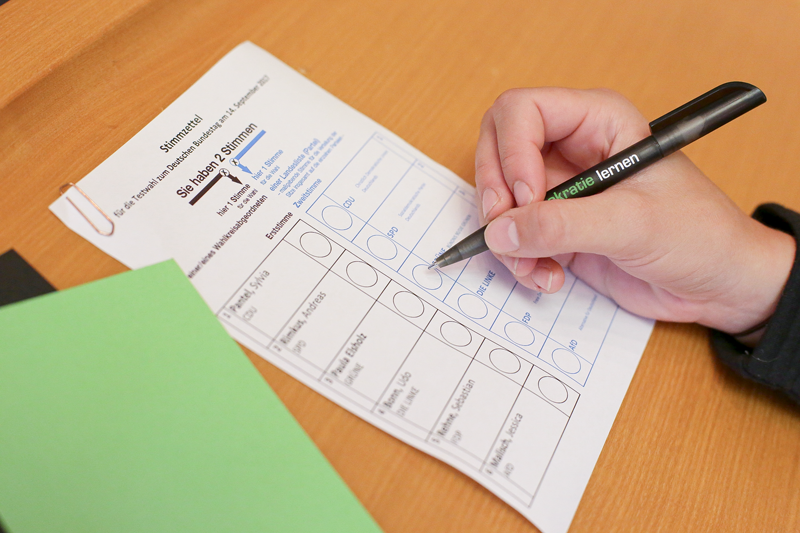 Person bearbeitet ihren Stimmzettel bei einer Wahl