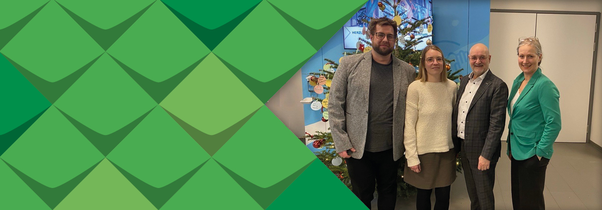 Ein Foto von Andreas Heither, Debora Stockmann, Alexander Pröbstl und Wibke Roth: Sie stehen vor einem Weihnachtsbaum in einem Flur der Pflegeschule des UK Bonn/alle tragen Blazer/alle lächeln/das Foto ist gerahmt von grünen Schmuckelementen der KSL.NRW