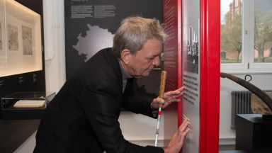 Ein Mann steht in der Zeche Zollern vor einer Infotafel mit Braille Ein Mann steht in der Zeche Zollern vor einer Infotafel mit Braille