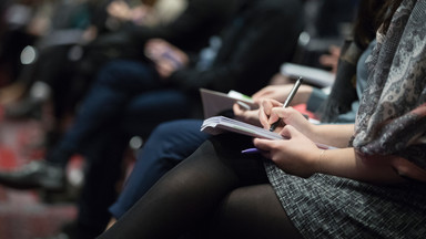 Fachkonferenz ( Der Bildausschnitt zeigt einen Teil eines Publikums auf einer Konferenz, die sich Notizen machen.