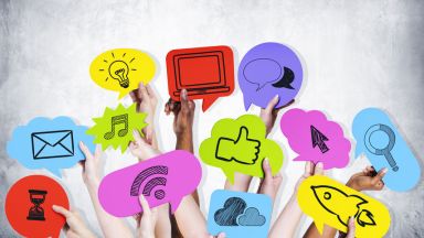 Das Bild zeigt viele Hände, die bunte Tafeln mit Social Media-Symbolen zeigen. Das Bild zeigt viele Hände, die bunte Tafeln mit Social Media-Symbolen zeigen.