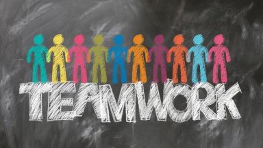Das Bild zeigt bunte Strichmännchen mit dem Wort TEAMWORK.