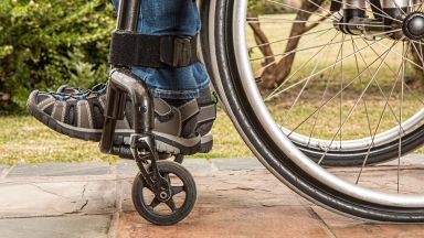 Räder eines Rollstuhls auf unebenem Belad